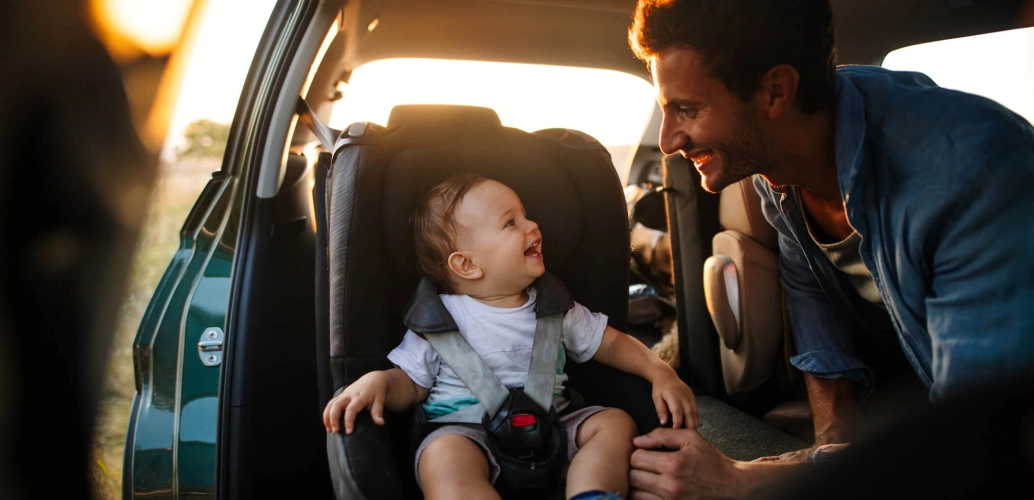 Homem coloca bebê na cadeirinha do carro.