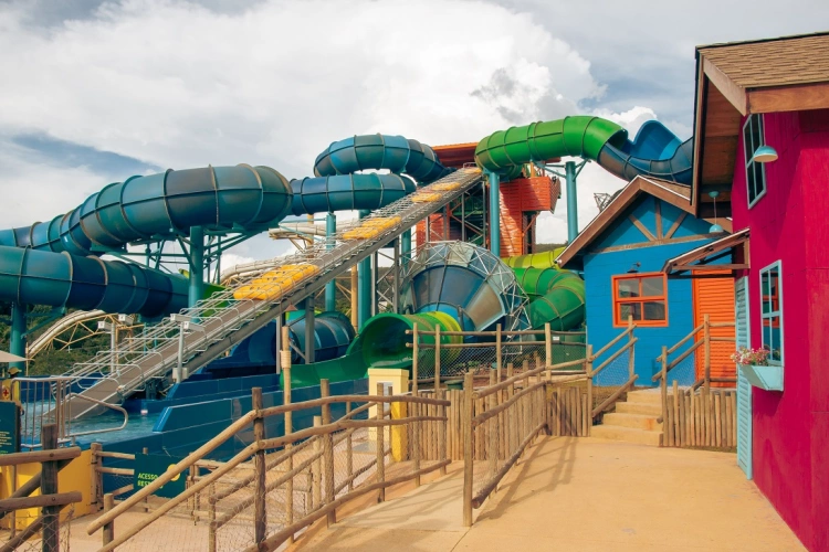 Um toboágua multicolorido com queda para uma piscina dentro de um parque de diversões
