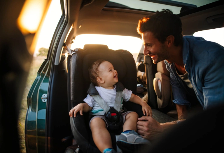 Homem coloca bebê na cadeirinha do carro.
