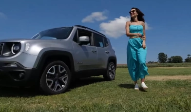 Mulher em pé ao lado de carro cinza estacionado em gramado