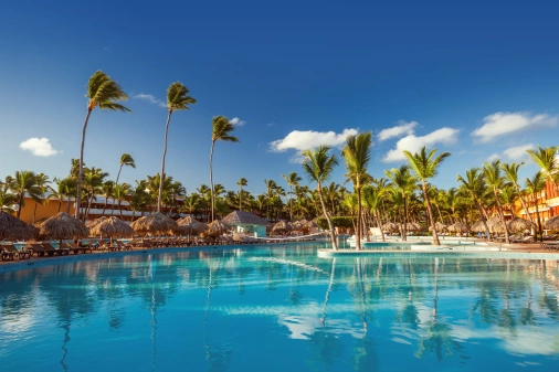 Piscina de um resort em Punta Cana, rodeada por enormes palmeiras em um dia ensolarado