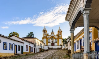 Uma rua histórica tranquila na cidade de Tiradentes, em Minas Gerais, com casas coloniais e uma igreja barroca ao fundo