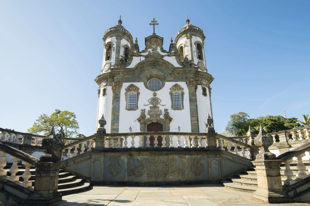 Fachada de igreja barroca na cidade histórica mineira de São João del Rei. No plano frontal, duas escadas, uma direcionada para o lado direito e outra para o esquerdo.
