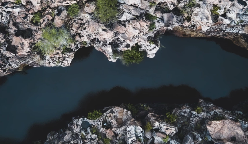 Vista de cima do Cânion Rio Poti. Paredões rochosos nas duas laterais de um rio de coloração escura.