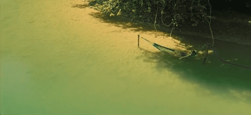 Pessoa acomodada em rede de descanso rio de de água verde