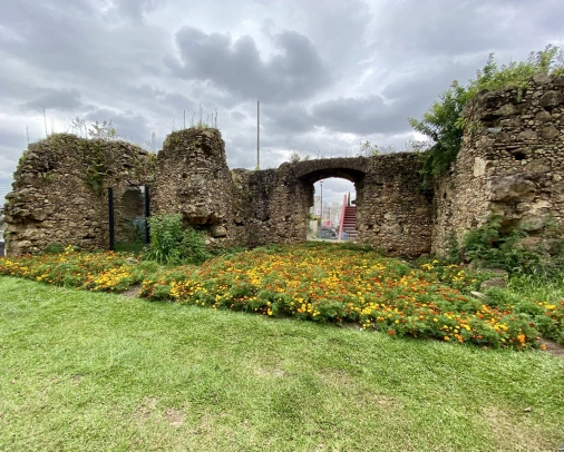Muros de pedra que representam ruínas contrastam com um jardim florido