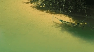 Pessoa acomodada em rede de descanso rio de de água verde