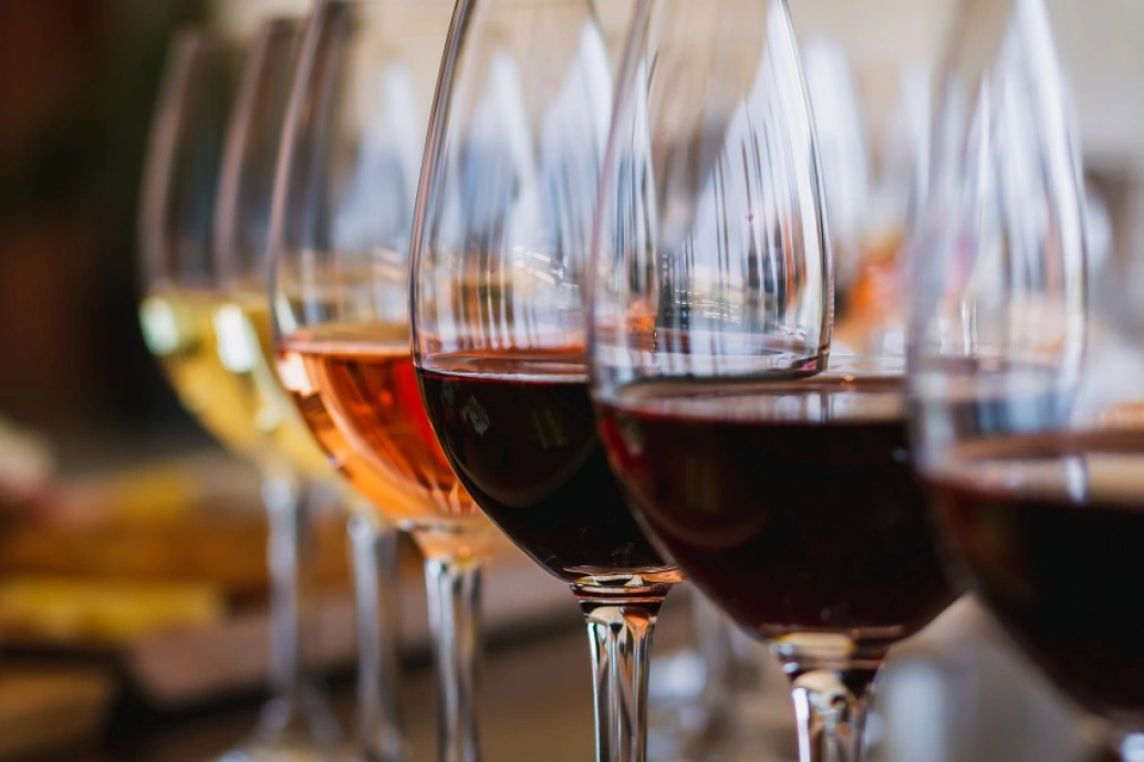 Seis taças de vinho cheias até a metade com a bebida. Vinhos tintos, rosés e brancos.