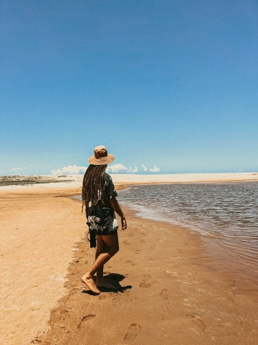 Rapaz em pé contempla praia deserta em dia ensolarado