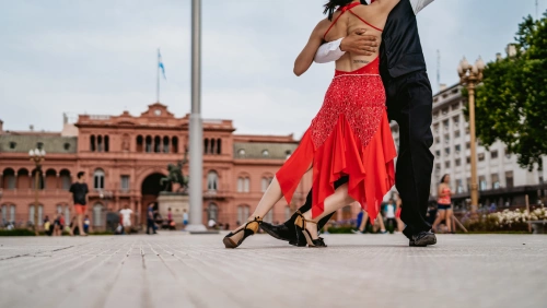 Casal latino dançando tango na Plaza de Mayo, na cidade de Buenos Aires, Argentina, à luz do dia.