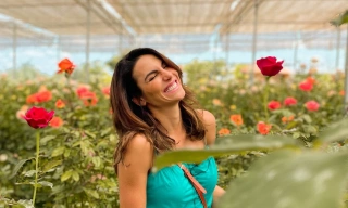 Mel Fronckowiak sorrindo dentro de jardim cheio de rosas
