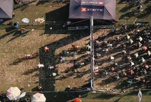 Vista aérea de vários ciclistas concentrados na fila de largada em evento esportivo
