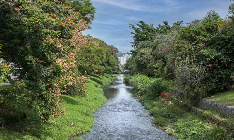 Extenso rio margeado por vegetação na cidade de Poços de Caldas.