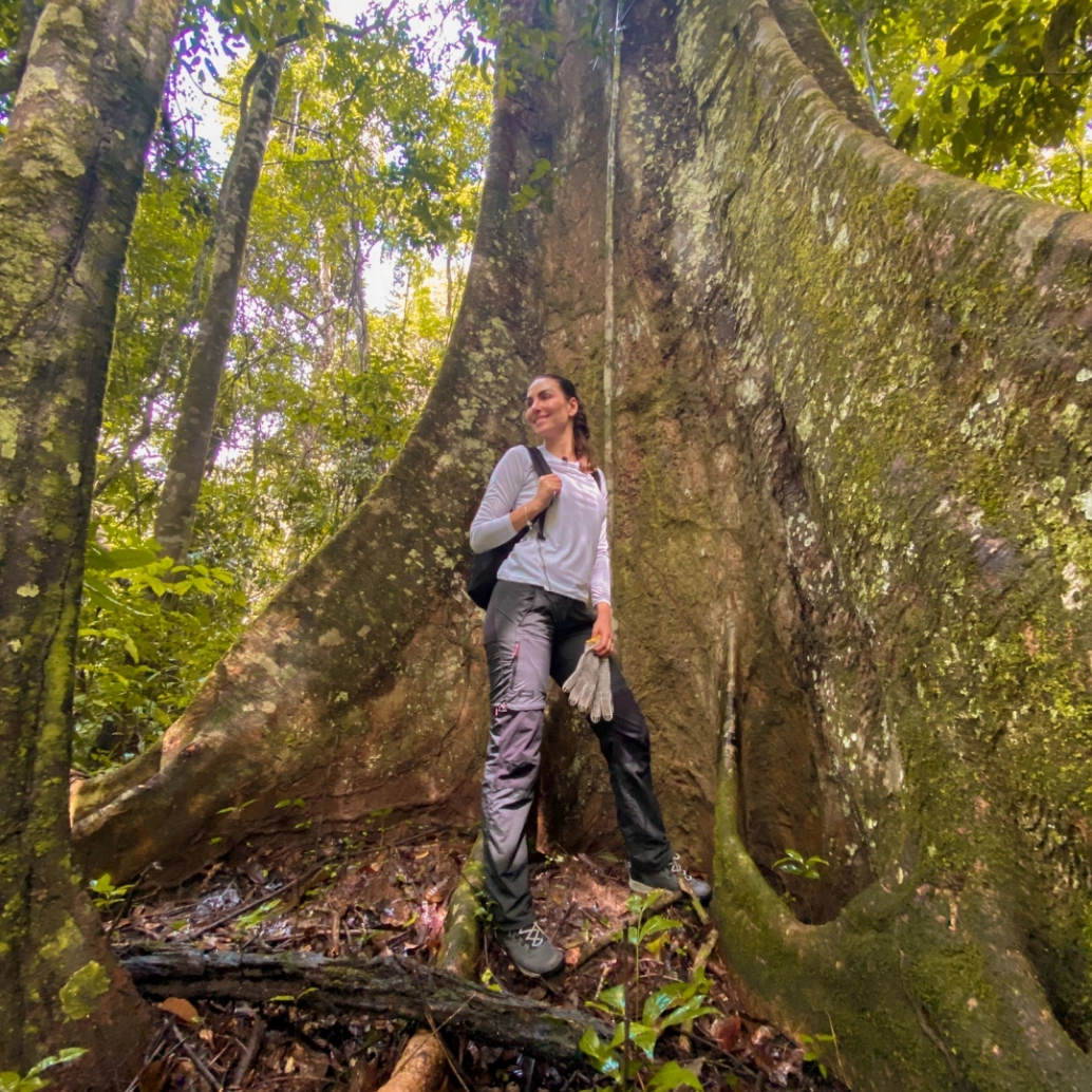 Mel Fronckowiak posando ao lado do tronco de uma enorme castanheira.