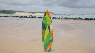 Prancha de surfe posicionada em praia em dia ensolarado