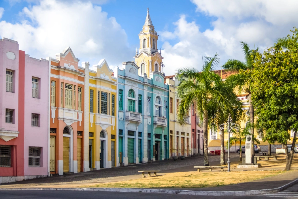 Prédios coloridos enfileirados em frente a uma pequena praça de cidade pacata