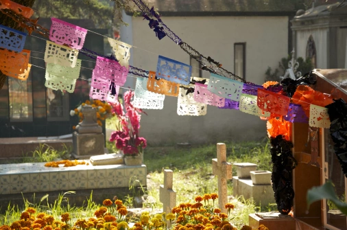 Sepulturas decoradas com flores e papéis coloridos na celebração de Dia dos Mortos no México