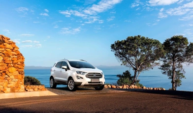 Ford EcoSport branco estacionado com o mar e o céu azul ao fundo.
