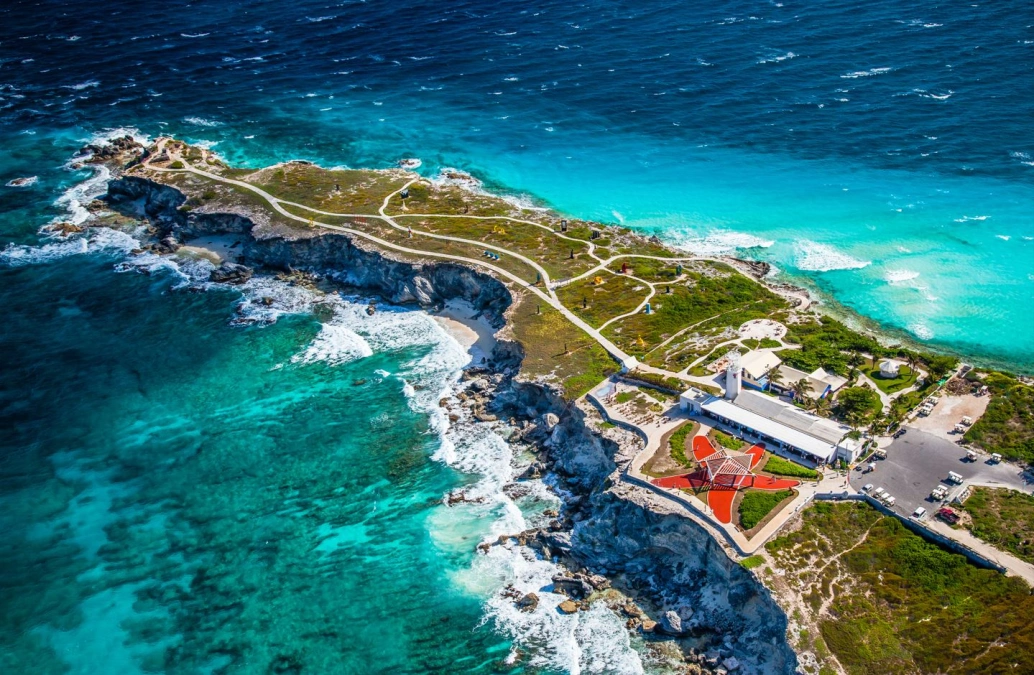 Foto aérea de ilha caribenha envolta a mar translúcido verde-azulado.