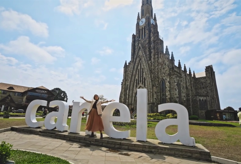 Mulher posa em frente à letreiro da cidade de Canela em Rio Grande do Sul