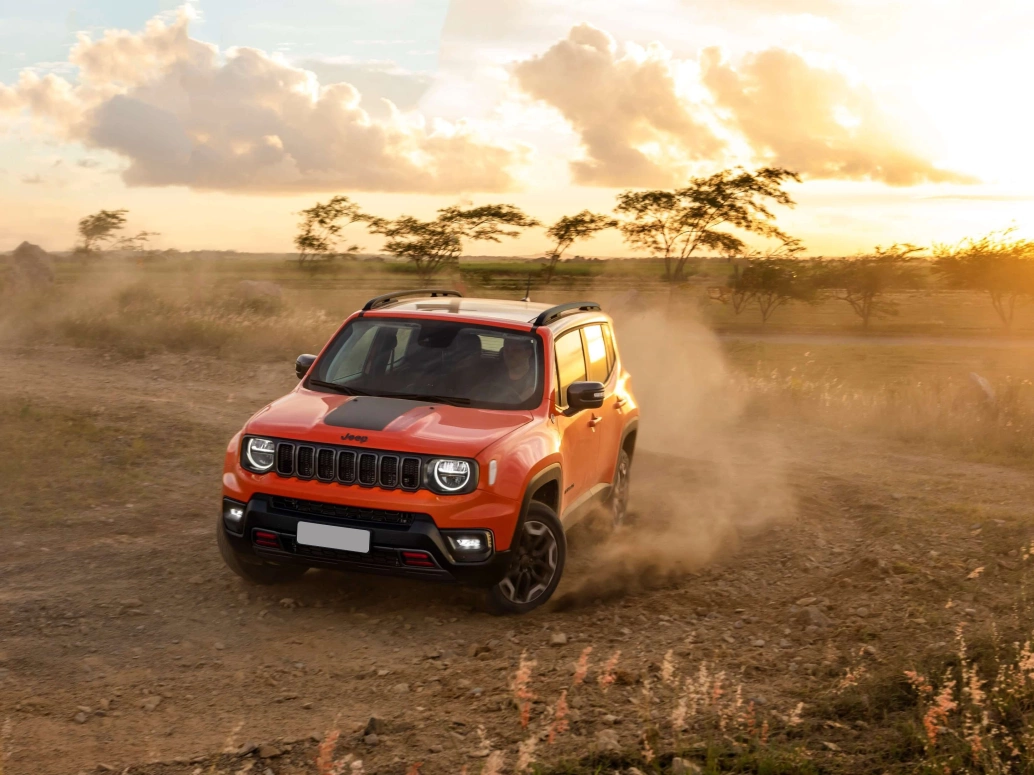 Jeep Renegade Trailhawk laranja fazendo uma manobra e levantando poeira em uma estrada de terra.