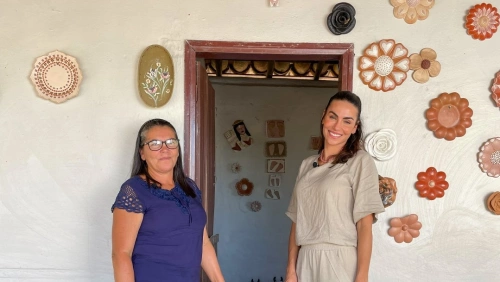 Mel Fronckowiak e a artista Zezinha Gomes em frente à casa decorada com cerâmicas artesanais em estilo próprio da arte de Turmalina, no Jequitinhonha - MG.