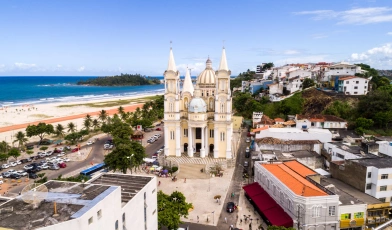 Vista aérea da cidade de Ilhéus, Bahia. Destaca-se uma igreja imponente no centro da imagem, e uma praia na margem esquerda
