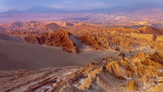 Vista aérea de um vale repleto de formações rochosas e dunas de areia ao entardecer
