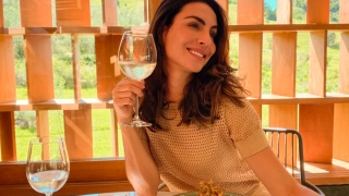 Mulher segura taça de vinho branco durante refeição em restaurante ao ar livre