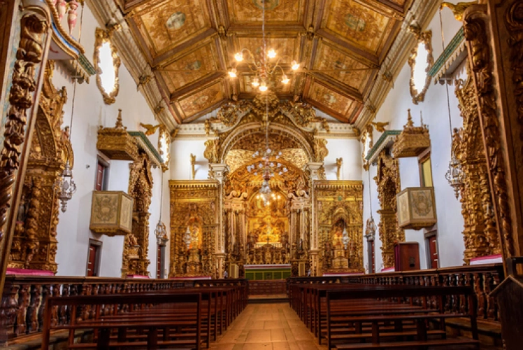 Interior de igreja ornamentada com peças em ouro, principalmente no altar