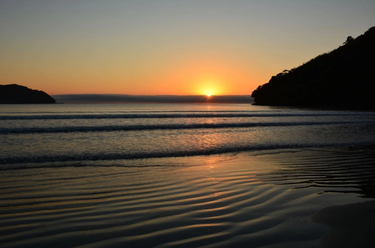 Um belo nascer do sol visto desde a areia da praia. Há pequenas ondas no mar