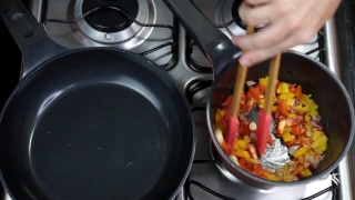 Pessoa misturando vegetais dentro de panela sobre fogão aceso