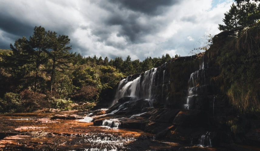 Paisagem da Cachoeira da Cabeceira localizada no Paraná. Águas da cachoeira caem pelas pedras cercas de vegetação nativa.