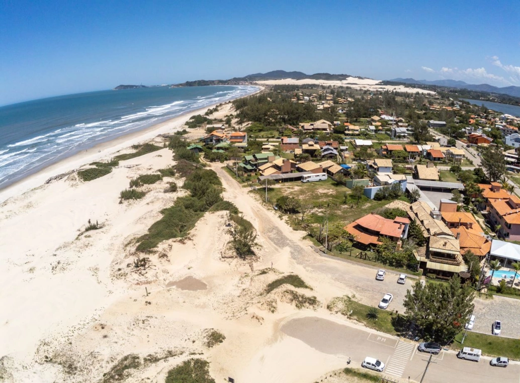 Foto tirada por drone focalizando aldeia à beira da praia e vegetação.