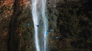 Vista frontal de cachoeira na Chapada dos Guimarães com belas araras azuis voando è frente