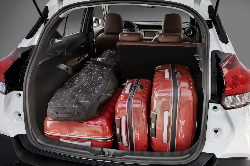 Nissan Kicks branco com o porta-malas aberto e cheio de bagagens.