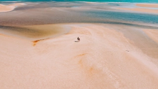 Vista aérea de um enorme banco de areia que se forma à beira de um rio que encontra com as águas do mar em um dia ensolarado