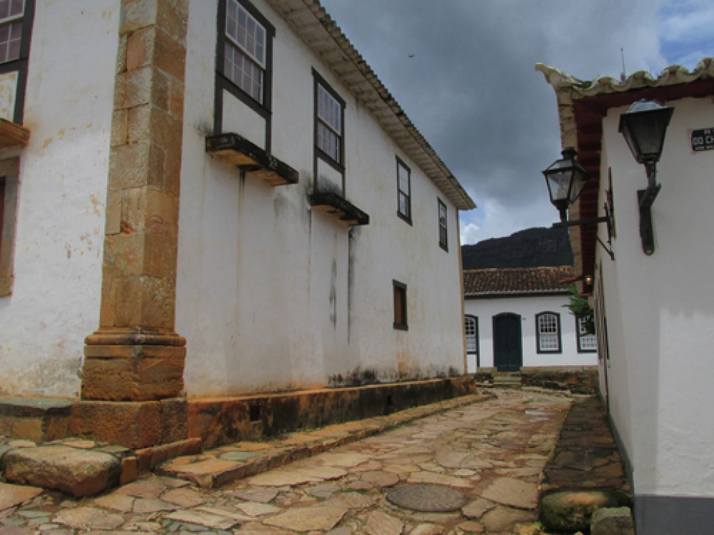 Pequeno beco com chão de pedra entre casas de arquitetura colonial