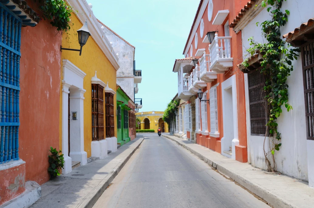 Estreita rua asfaltada envolta de casas coloniais coloridas em Cartagena, cidade colombiana.
