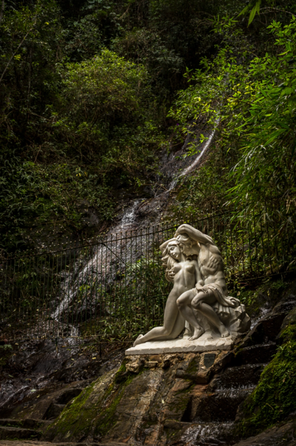 Estátua de homem e mulher em meio à vegetação na Fonte dos Amores, Poços de Caldas