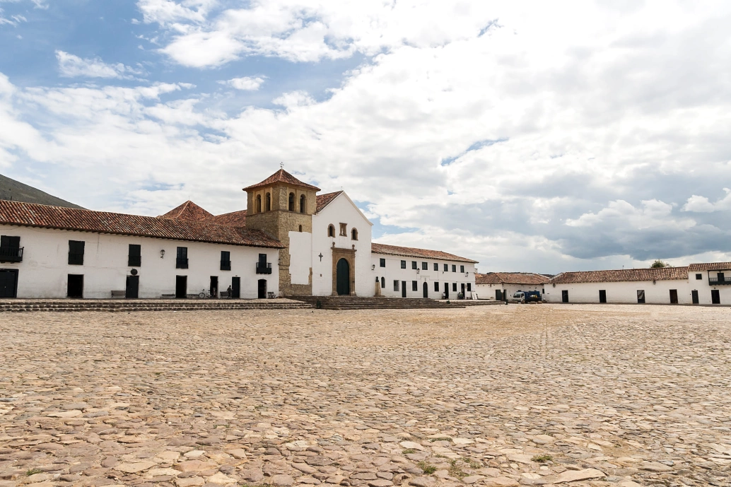 Vista panorâmica de uma praça com rua de pedra e uma igreja com arquitetura colonial
