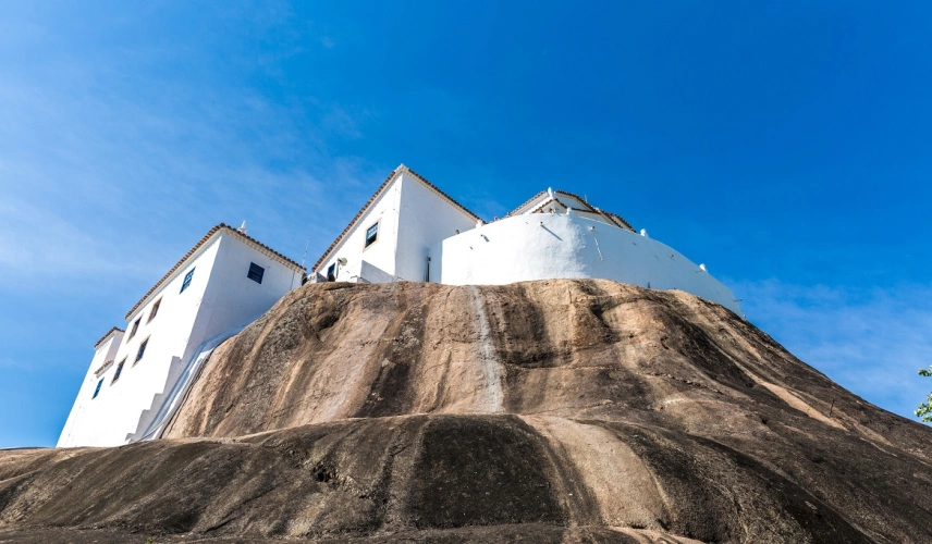 Um convento pintado de branco construído sob uma enorme pedra