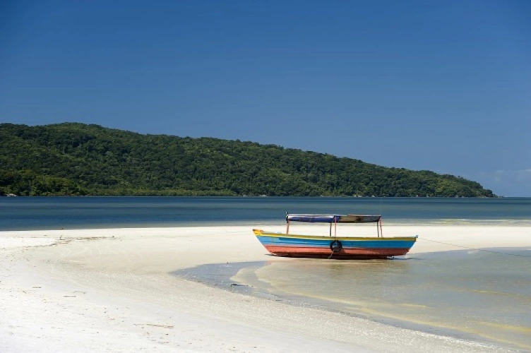 Barco estacionado em areias claras de praia deserta em dia ensolarado