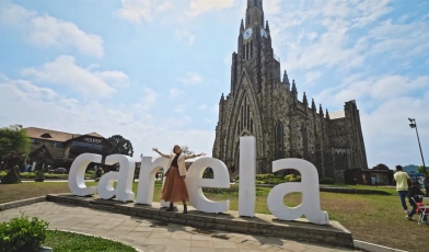 Mulher posa em frente à letreiro da cidade de Canela em Rio Grande do Sul