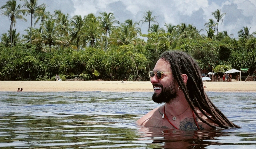 Músico Gabriel Elias sorrindo mergulha em rio em dia claro