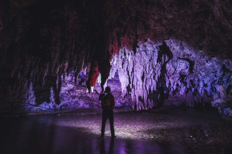 Silhueta de homem em interior de gruta. Se destaca a cor roxa.