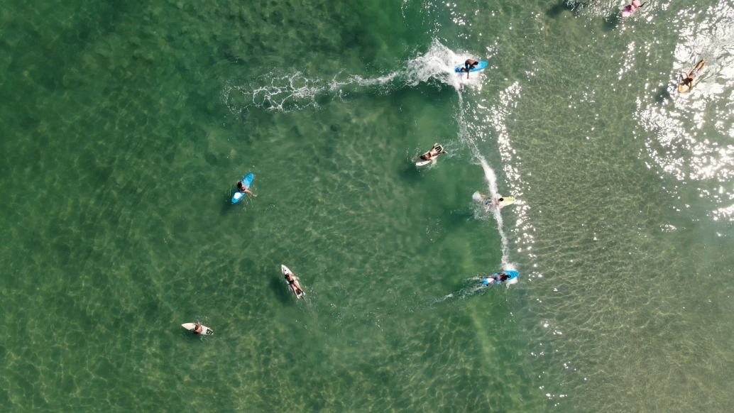 Vista aérea do mar com alguns surfistas em suas pranchas