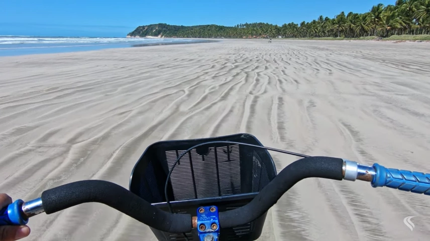 Guidão de bicicleta em areias brancas de praia deserta cercada por coqueiros
