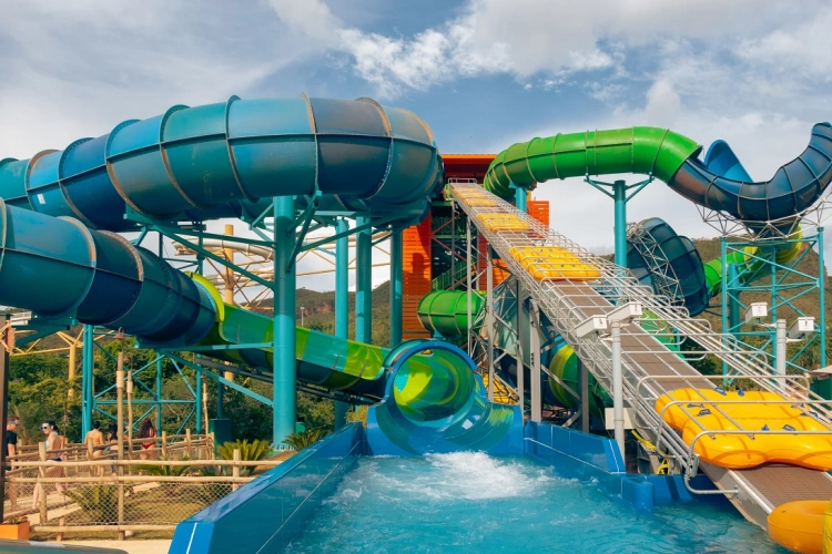 Um toboágua multicolorido com queda para uma piscina dentro de um parque de diversões