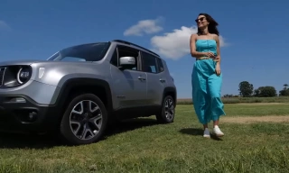 Mulher em pé ao lado de carro cinza estacionado em gramado
